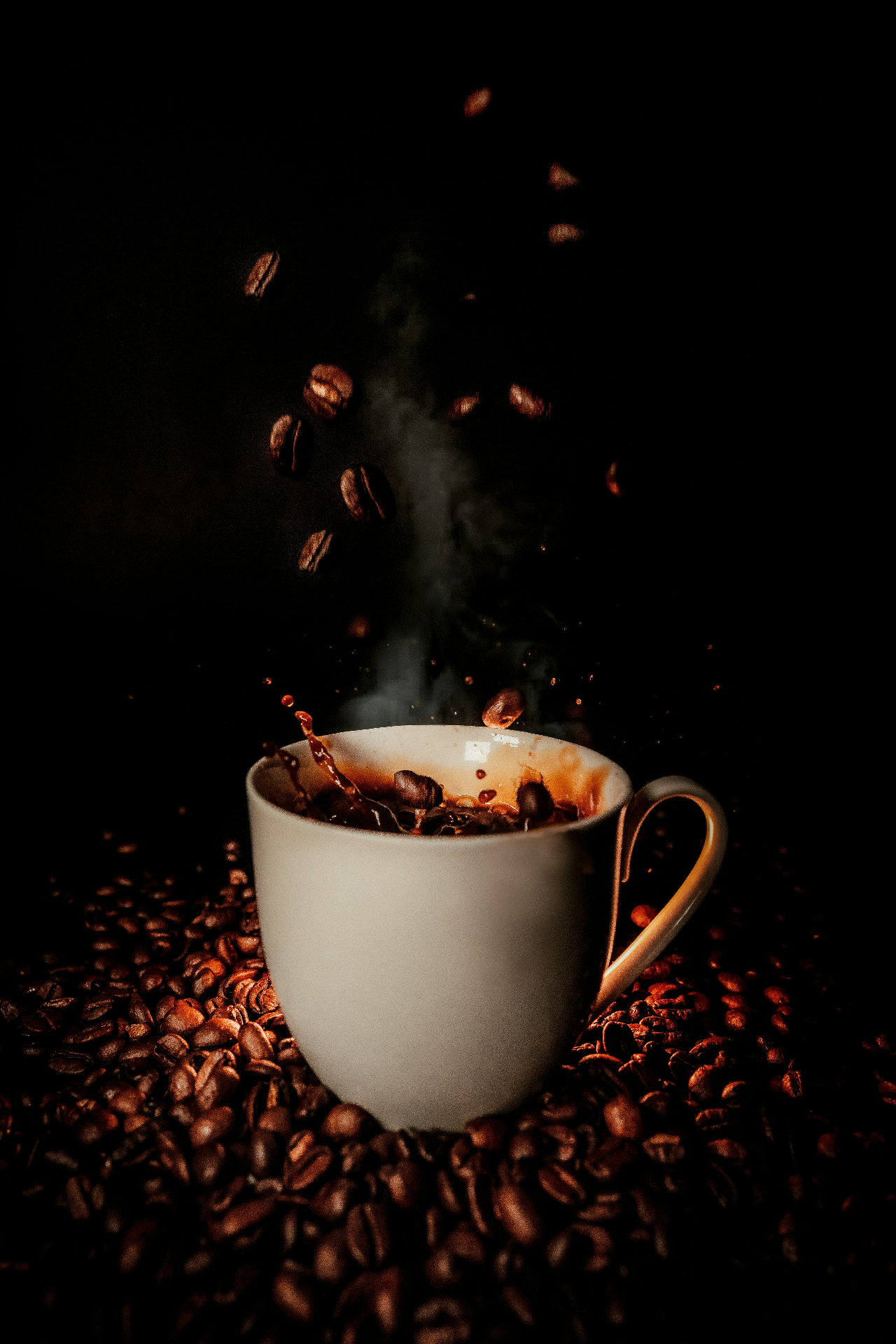 Coffee beans falling into a steaming cup